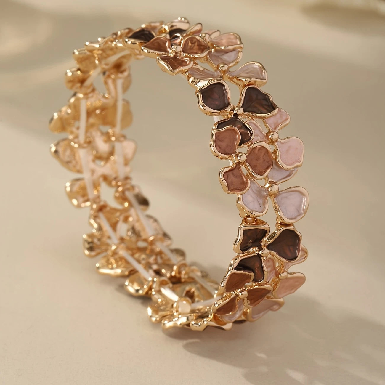 Elastic gold bangle with pastel enamel floral motifs in mauve, blush, and taupe – feminine stretch bracelet for women