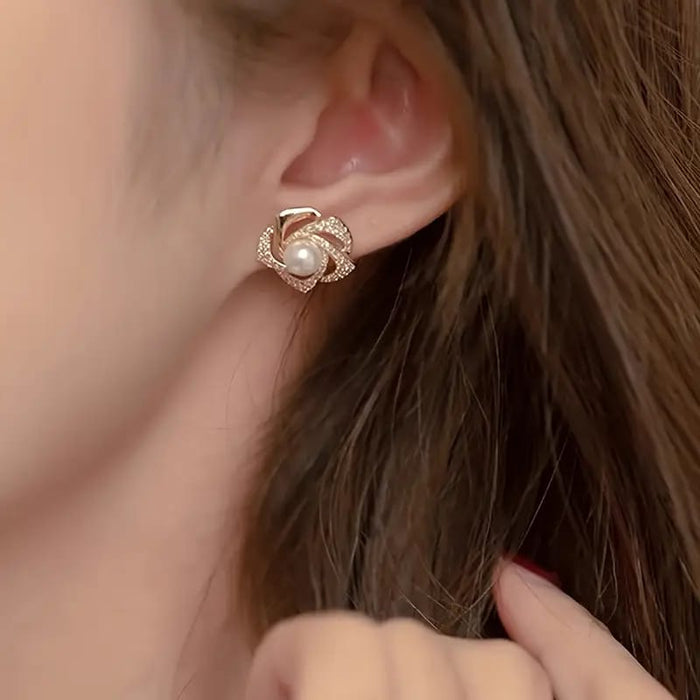 Gold floral swirl stud earrings with pave crystals and a central faux pearl – elegant feminine jewelry for formal occasions