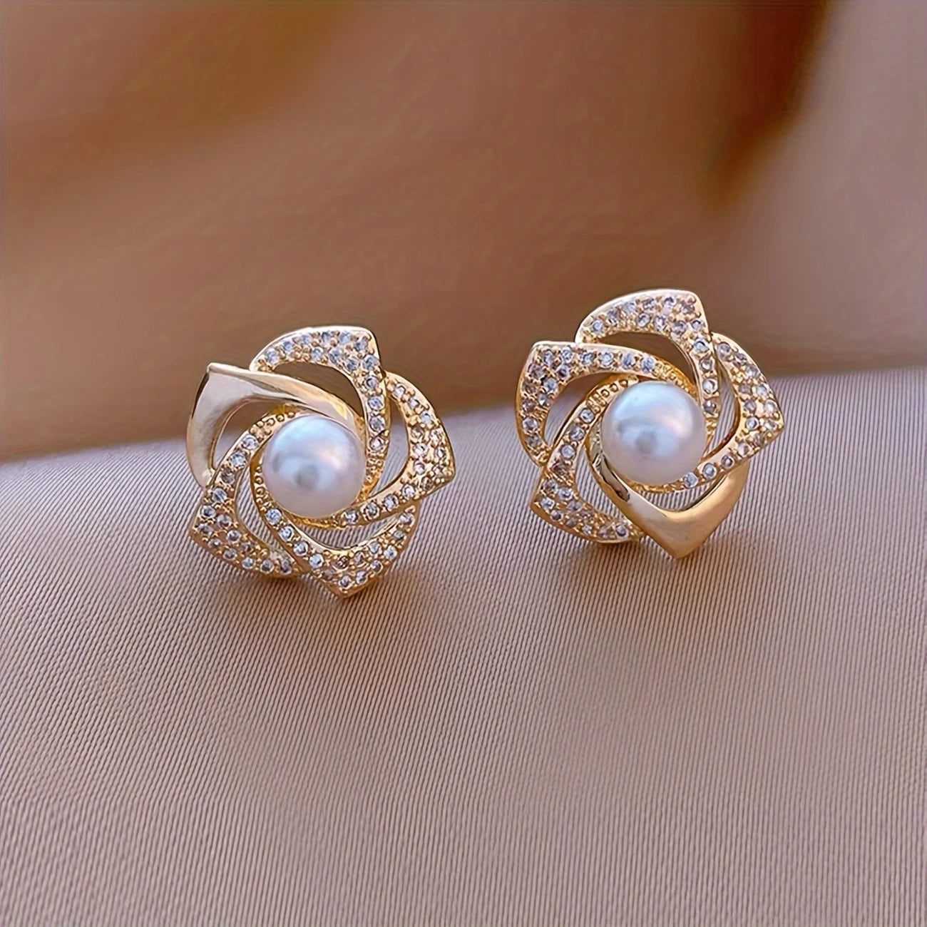 Gold floral swirl stud earrings with pave crystals and a central faux pearl – elegant feminine jewelry for formal occasions