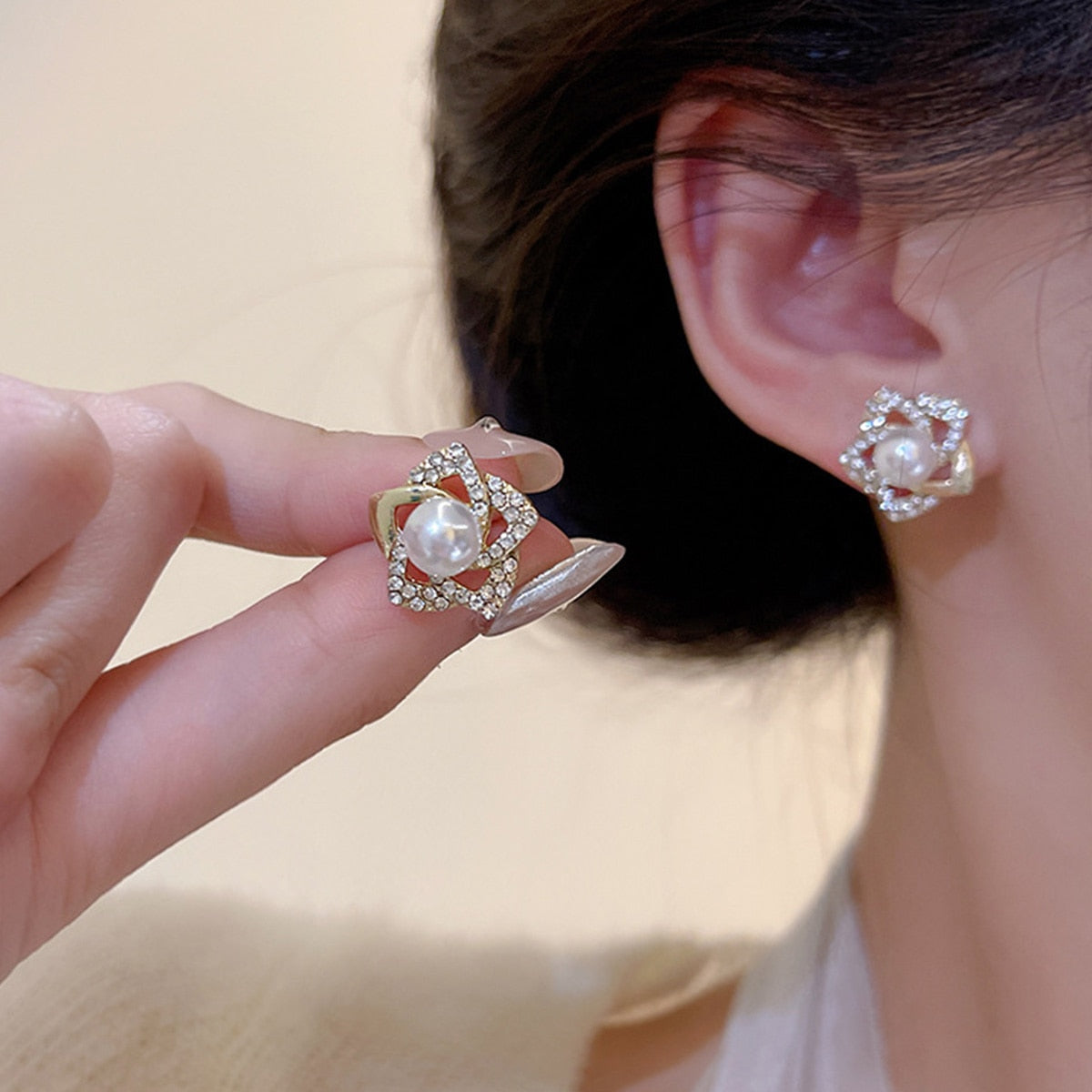 Gold floral swirl stud earrings with pave crystals and a central faux pearl – elegant feminine jewelry for formal occasions