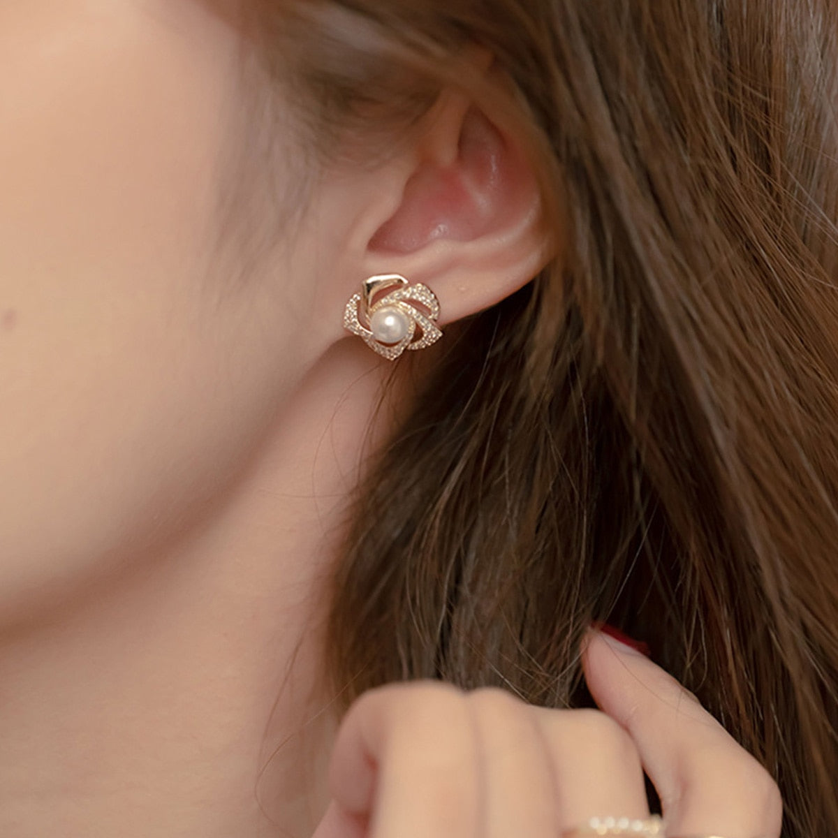 Gold floral swirl stud earrings with pave crystals and a central faux pearl – elegant feminine jewelry for formal occasions