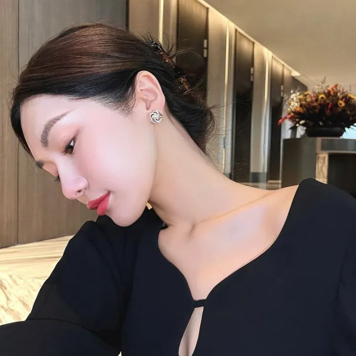 Gold floral swirl stud earrings with pave crystals and a central faux pearl – elegant feminine jewelry for formal occasions